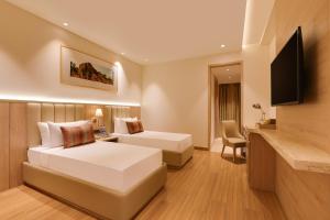 a hotel room with two beds and a flat screen tv at Lemon Tree Hotel, Motihari in Motīhāri