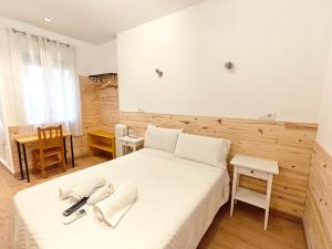 a bedroom with a large white bed and a table at Hostal Aliste in Madrid