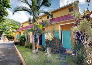 a house with a palm tree in front of it at L'Oasis de L'Anse Bleue in Le Diamant