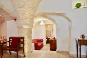 Una sala de estar con un arco de piedra y un sofá rojo. en Trullo Stella Luxury Trullo, en Alberobello