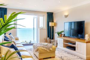 a living room with a flat screen tv and a large window at Tranquil Shores in Carbis Bay