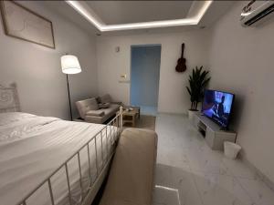 a bedroom with a bed and a couch and a television at استديو غرفة نوم بدخول ذكي in Jazan