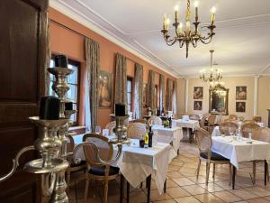 a restaurant with white tables and chairs and a chandelier at Hotel Casa Borghese in Senningerberg