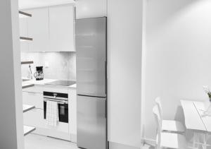 a kitchen with white cabinets and a refrigerator at Togton Premium Suite Växjö in Växjö