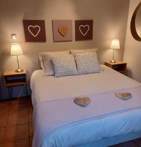 a bedroom with a large white bed with two lamps at le Roy de coeur in Riquewihr +3 photos
