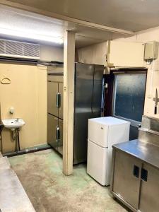 an empty kitchen with a refrigerator and a sink at 波浮とみや全部屋個室 in Oshima