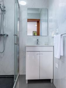 a white bathroom with a sink and a shower at Solar do Pico Studio in Ponta Delgada