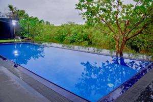 a swimming pool with blue water and trees in the background at Elite Black Villa in Bandaragama