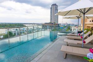 a pool on the roof of a building with benches and an umbrella at The IRIS SIGNATURE HOTEL AND SPA in Can Tho