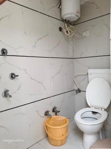 a bathroom with a toilet and a bucket in it at Shree Krishna Hotel in Udaipur