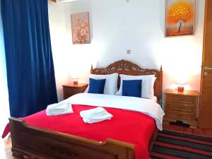 a bedroom with a red and white bed with towels on it at Cleopatrahouse in Stemnitsa