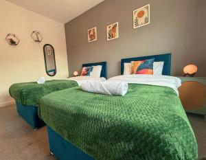 a bedroom with two beds with green sheets and pillows at Spacious 3bed, Sleeps5, Parking in Birmingham