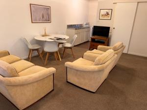 a living room with couches and a table and a kitchen at Wairoa Motel in Wairoa