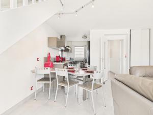 eine weiße Küche und ein Esszimmer mit Tisch und Stühlen in der Unterkunft Maison en résidence - piscine - 2 adultes 2 enfants in Le Croisic