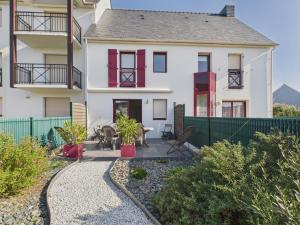 ein weißes Haus mit roten Fenstern und einem Zaun in der Unterkunft Maison en résidence - piscine - 2 adultes 2 enfants in Le Croisic