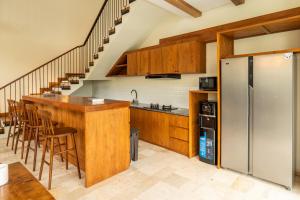 a kitchen with wooden cabinets and a bar with stools at Tuluscoliving Villa Kuta 1, 4 Bedroom & 5 Bathroom in Ngurah Rai International Airport