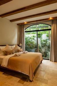 a bedroom with a large bed and a large window at Tuluscoliving Villa Kuta 1, 4 Bedroom & 5 Bathroom in Ngurah Rai International Airport +54 photos