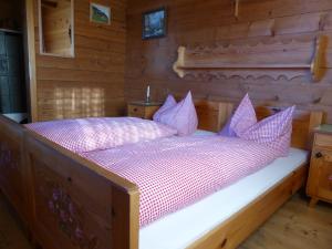 a bed in a wooden cabin with purple pillows at Kristemoarhütte in Untergaimberg