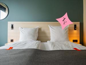 a bed with two white pillows and a pink sign on it at Citybox Brussels in Brussels