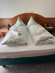 a bed with three pillows on top of it at Hotel & Restaurant Garda in Darmstadt
