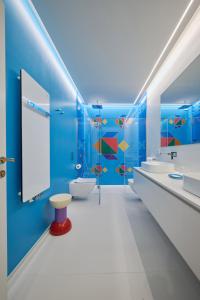 a bathroom with blue walls and white fixtures at Byblos Art Hotel Villa Amistà in San Pietro in Cariano