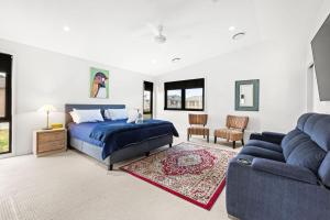 een slaapkamer met een blauw bed en een bank bij Whale Watcher - Beachfront with Spa in Culburra Beach