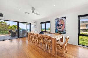 een eetkamer met een houten tafel en stoelen bij Whale Watcher - Beachfront with Spa in Culburra Beach