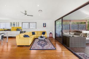 een woonkamer met een gele bank en een keuken bij Whale Watcher - Beachfront with Spa in Culburra Beach +26 foto's