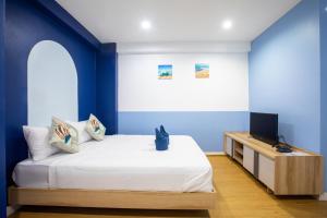 a bedroom with blue walls and a bed with a television at PanoSea Bangsaen in Ban Bang Saen (1)