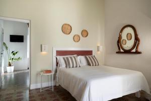 a bedroom with a white bed and a mirror on the wall at Relais San Martino - Salento in Taviano