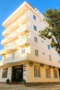 a white building with a tree in front of it at Trường Sa Hotel Cửa Lò Beach in Cửa Lò