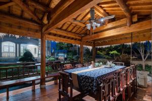 een houten paviljoen met een tafel, stoelen en een plafondventilator bij Floral Luxury Hengdian Jiuqilu B&B in Longfengshan