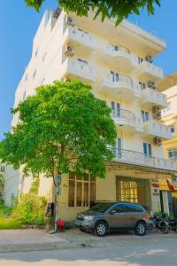 a car parked in front of a building with a tree at Trường Sa Hotel Cửa Lò Beach in Cửa Lò