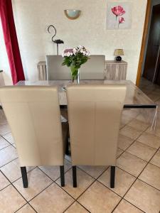einen Tisch mit zwei Stühlen und eine Vase mit Blumen darauf in der Unterkunft Gîte à la Ferme in Las Pelies