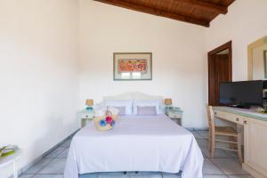 Un dormitorio con una cama blanca y un televisor. en Li Suari Club Village, en San Teodoro
