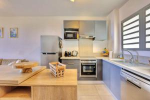 Una cocina con electrodomésticos de acero inoxidable y encimera de madera. en Le Nocéa - apt T3 Saint Leu, en Saint-Leu