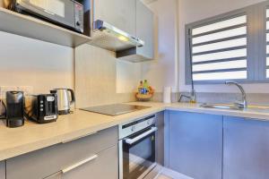 una cocina con fregadero y estufa horno superior en Le Nocéa - apt T3 Saint Leu, en Saint-Leu
