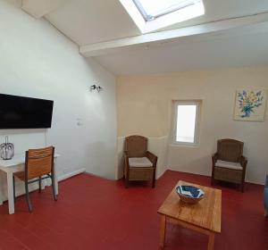 a living room with a tv and a table and chairs at La Guitoune du Pélican in Puisserguier