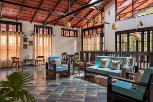 a lobby with blue couches and tables and windows at Kumberi Manor by Raho - Heritage Retreat in Coorg in Ammatti