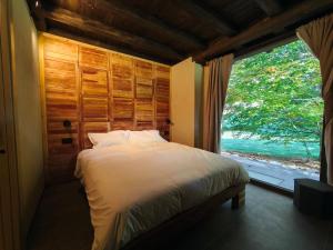 een slaapkamer met een bed en een groot raam bij Rèfol Lodge Val di Ledro in Pur