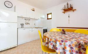een keuken en eetkamer met een tafel en gele stoelen bij Robinson Delphinus in Gdinj