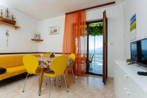 een eetkamer met een tafel, stoelen en een televisie bij Robinson Delphinus in Gdinj