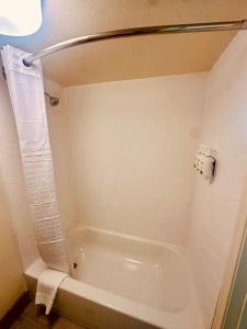a white bath tub in a bathroom with a shower at Ramada by Wyndham Merced in Merced