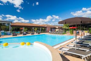 una piscina con tumbonas y sombrilla en Li Suari Club Village, en San Teodoro