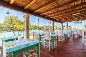 Un restaurante con mesas y sillas y una piscina. en Li Suari Club Village, en San Teodoro