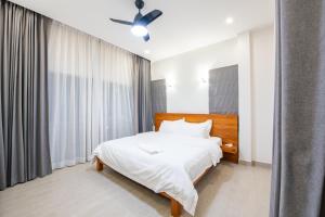 a bedroom with a white bed and a ceiling fan at Tidal Coast Villa Pattaya in Ban Huai Yai