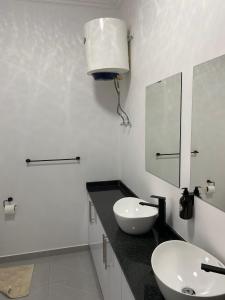 a white bathroom with a sink and a mirror at Villa Djonasse, a Residence of Exellency in Fombeni