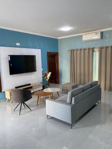 a living room with a couch and a tv at Villa Djonasse, a Residence of Exellency in Fombeni