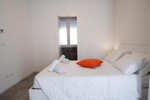 a white bed with an orange pillow and towels on it at The Rooftop in Bologna