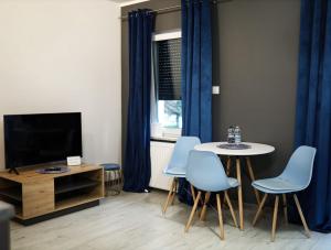 a living room with a table and chairs and a tv at Apartament Oslo in Pniewy